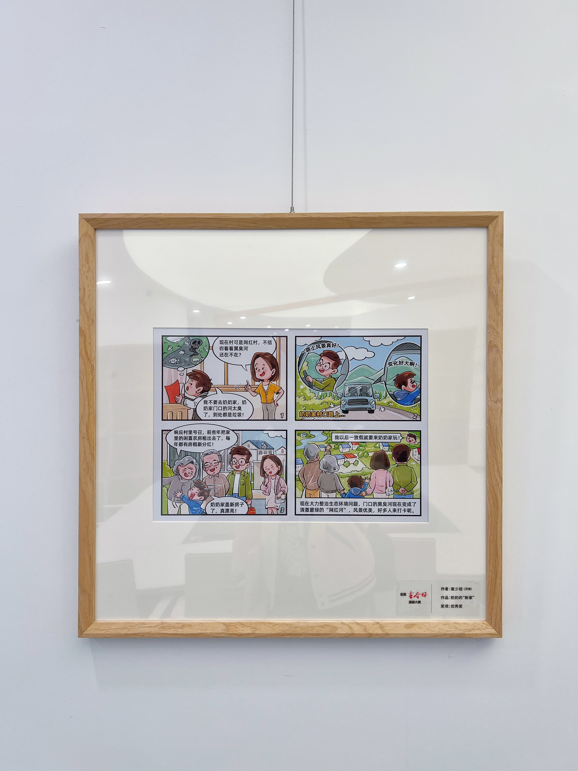 首届米谷杯漫画大展作品《奶奶的“新家”》展出照片,展签标注优秀奖。